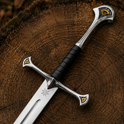 Close-up Anduril sword hilt with black wrapped grip, sweeping silver-coloured guard, pommel and gold accent details