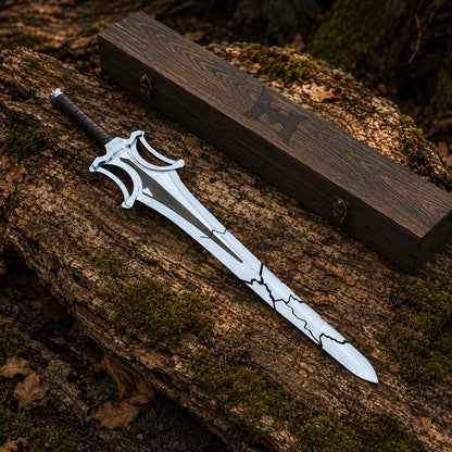 He-Man broken power sword displayed beside closed dark wooden box on rustic woodland surface