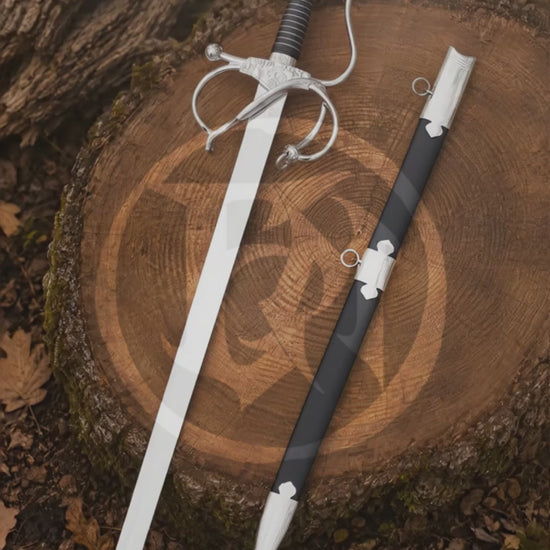 Cinematic vertical showcase of the El Cid rapier replica and black scabbard displayed on a woodland tree stump, highlighting the polished blade, wrapped grip and ornate swept-hilt design.