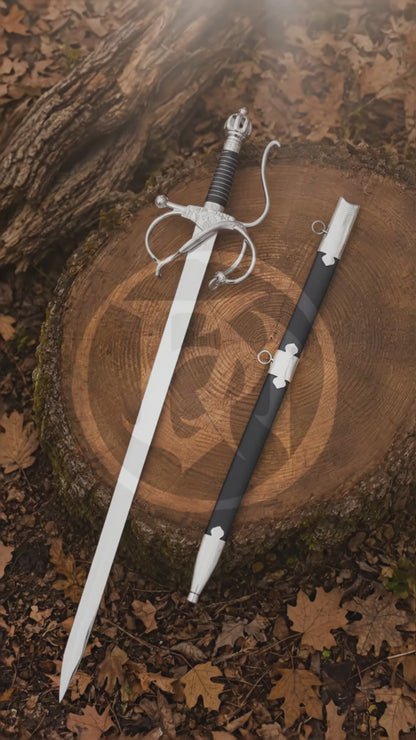 Cinematic vertical showcase of the El Cid rapier replica and black scabbard displayed on a woodland tree stump, highlighting the polished blade, wrapped grip and ornate swept-hilt design.