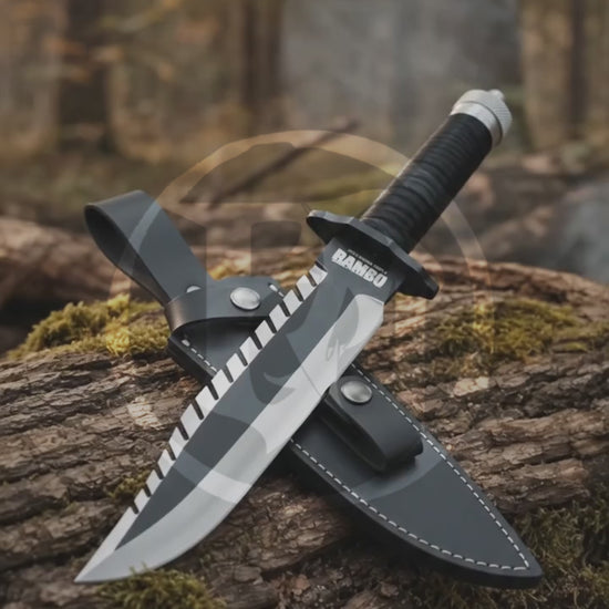Cinematic woodland showcase of the Rambo First Blood Part II knife replica featuring its matte black sawback blade, cord-wrapped handle, printed detailing and stitched leather sheath.