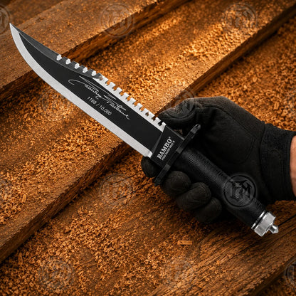Hand-held Rambo II survival knife replica showing matte-black blade, sawback spine and numbered signature detailing.